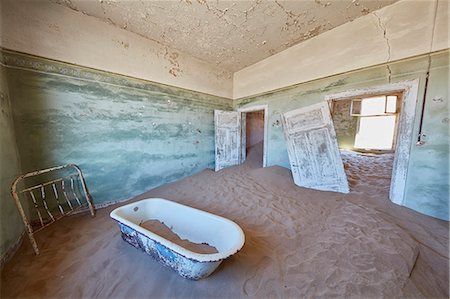 A view of a bathroom in a derelict building full of sand. Stock Photo - Premium Royalty-Free, Code: 6118-09018130