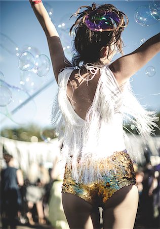 Rear view of young woman at a summer music festival wearing golden sequinned hot pants, dancing among the crowd. Photographie de stock - Premium Libres de Droits, Code: 6118-09018287