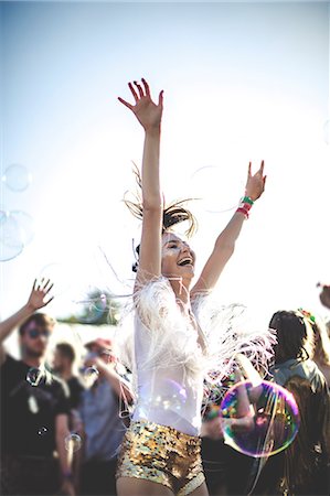 festivals - Young woman at a summer music festival wearing golden sequinned hot pants, dancing among the crowd. Photographie de stock - Premium Libres de Droits, Code: 6118-09018288
