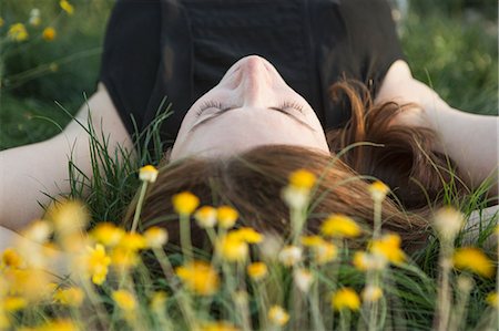 simsearch:6118-09018327,k - A woman in a black vest top and jeans lying on the grass with her hands behind her head. Photographie de stock - Premium Libres de Droits, Code: 6118-09018343