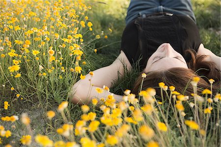 simsearch:6118-09018328,k - A woman in a black vest top and jeans lying on the grass with her hands behind her head. Photographie de stock - Premium Libres de Droits, Code: 6118-09018344