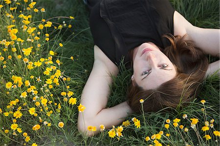 simsearch:6118-09018328,k - A woman in a black vest top and jeans lying on the grass with her hands behind her head. Photographie de stock - Premium Libres de Droits, Code: 6118-09018345