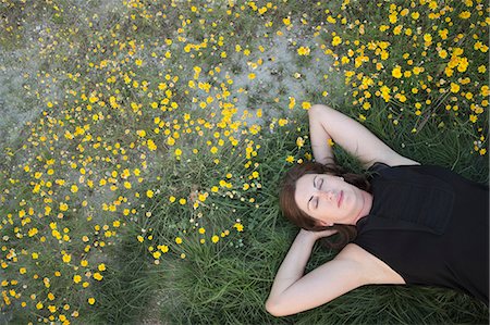 simsearch:6118-09018328,k - A woman in a black vest top and jeans lying on the grass with her hands behind her head. Photographie de stock - Premium Libres de Droits, Code: 6118-09018346