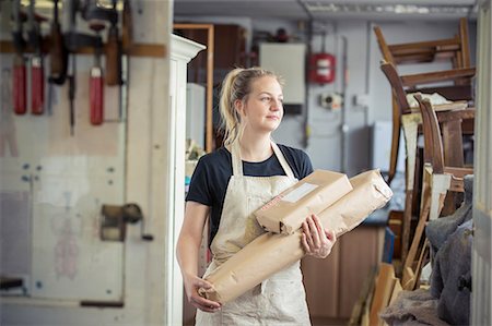 packet - A young woman in a workshop, holding two packages wrapped in brown packaging paper, ready for despatch. Foto de stock - Sin royalties Premium, Código: 6118-09018355