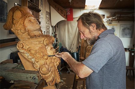 simsearch:6118-09018535,k - A craftsman, a wood carver working on a wooden female ship's figurehead held in a vice on the workbench of his workshop. Stock Photo - Premium Royalty-Free, Code: 6118-09018392