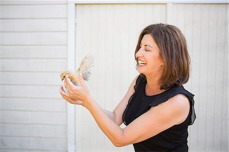 simsearch:6118-09018328,k - A woman holding a small fluffy chick, a baby bird in her two hands. Photographie de stock - Premium Libres de Droits, Code: 6118-09018329