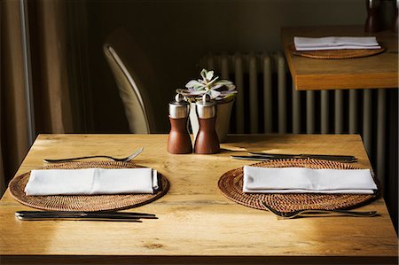 simsearch:6118-08521776,k - Wooden table set with place mats, napkins and cutlery in a restaurant. Photographie de stock - Premium Libres de Droits, Code: 6118-09018407