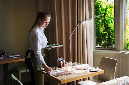 simsearch:614-07032195,k - Woman wearing apron setting table in a restaurant. Foto de stock - Royalty Free Premium, Número: 6118-09018413