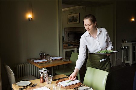 simsearch:614-07032195,k - Woman wearing apron setting table in a restaurant. Foto de stock - Royalty Free Premium, Número: 6118-09018414