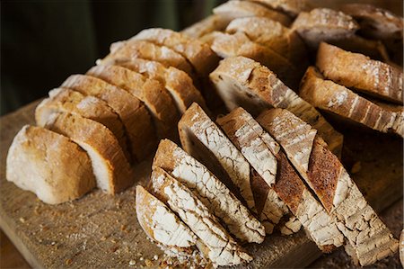 simsearch:6102-06777495,k - Close up of a freshly baked loaf of bread cut into slices. Photographie de stock - Premium Libres de Droits, Code: 6118-09018424