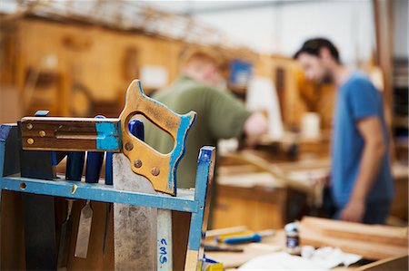 simsearch:6118-08947801,k - Close up of hand tools in boat-builder's workshop, two men working in background. Stock Photo - Premium Royalty-Free, Code: 6118-09018533