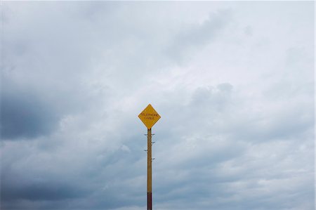 simsearch:6118-08883010,k - Yellow warning sign on pole against cloudy sky. Stock Photo - Premium Royalty-Free, Code: 6118-09018653