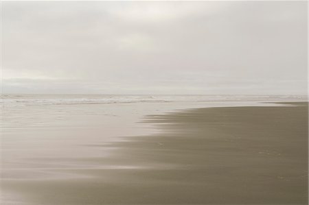 The beach at the waterline, and view out to sea with overcast sky and gathering dusk. Stock Photo - Premium Royalty-Free, Code: 6118-09018665