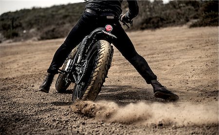 soil - Rear view low section view of man riding cafe racer motorcycle on a dusty dirt road. Stock Photo - Premium Royalty-Free, Code: 6118-09027922