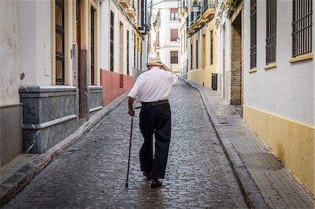 simsearch:6118-07203257,k - Rear view of elderly man with cane walking along cobbled street in Sevilla, Andalusia, Spain. Stock Photo - Premium Royalty-Free, Code: 6118-09028093