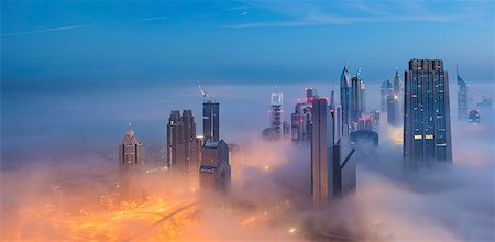 Cityscape with illuminated skyscrapers above the clouds in Dubai, United Arab Emirates at dusk. Stock Photo - Premium Royalty-Free, Code: 6118-09028185