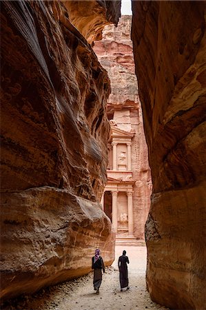 simsearch:6119-08518029,k - Two people walking through narrow rock formation towards rock-cut architecture of Al Khazneh or The Treasury at Petra, Jordan. Photographie de stock - Premium Libres de Droits, Code: 6118-09028126