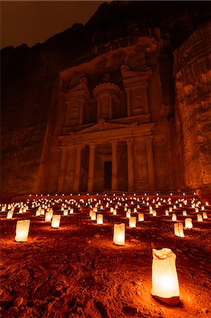 simsearch:6119-08518029,k - Exterior view of the rock caves and architecture of the facade in sandstone at Al Khazneh or The Treasury at Petra, Jordan at night. A red glow with small glowing lamps on the ground. Photographie de stock - Premium Libres de Droits, Code: 6118-09028128