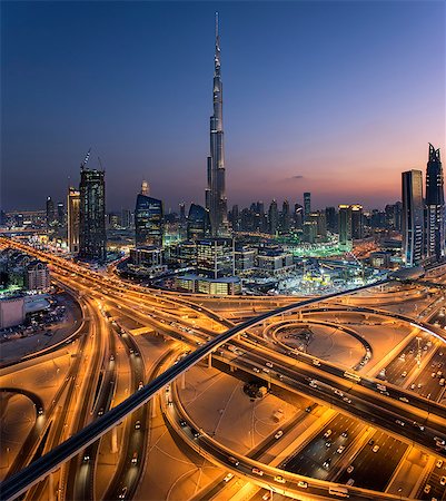 Cityscape of Dubai, United Arab Emirates at dusk, with the Burj Khalifa skyscraper and illuminated highways in the foreground. Stock Photo - Premium Royalty-Free, Code: 6118-09028248