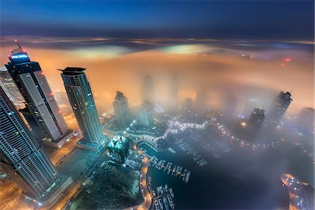 Aerial view of cityscape with illuminated skyscrapers above the clouds in Dubai, United Arab Emirates at dusk. Photographie de stock - Premium Libres de Droits, Code: 6118-09028213