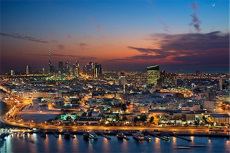 simsearch:6118-09028243,k - Cityscape of Dubai, United Arab Emirates at dusk, with illuminated skyscrapers in the distance. Stock Photo - Premium Royalty-Free, Code: 6118-09028214