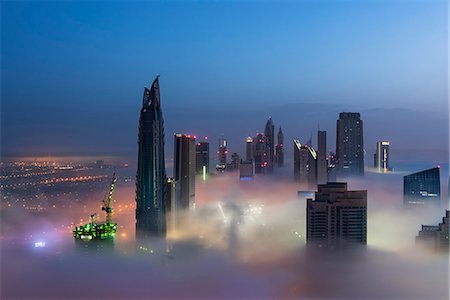 View of illuminated skyscrapers above the clouds in Dubai, United Arab Emirates. Stock Photo - Premium Royalty-Free, Code: 6118-09028216