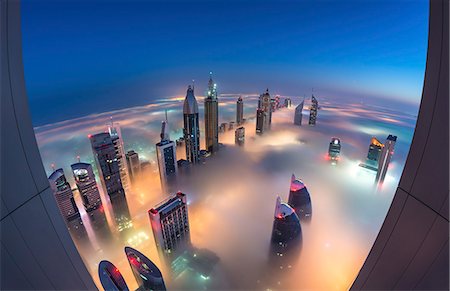 simsearch:649-08565623,k - Aerial view of cityscape with illuminated skyscrapers above the clouds in Dubai, United Arab Emirates at dusk. Foto de stock - Sin royalties Premium, Código: 6118-09028237