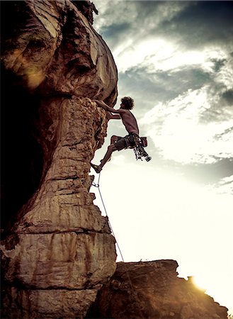 Mountaineer climbing a rock formation in a mountainous landscape. Stock Photo - Premium Royalty-Free, Code: 6118-09039108