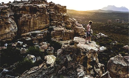 Mountaineer standing on top of a rock formation in a mountainous landscape. Photographie de stock - Premium Libres de Droits, Code: 6118-09039114