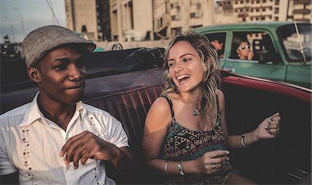 Two people riding through an urban environment in an open convertible classic car. Foto de stock - Sin royalties Premium, Código: 6118-09039130