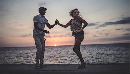 simsearch:6118-09039292,k - Two people dancing on a sea wall in front of the ocean at dusk. Foto de stock - Sin royalties Premium, Código: 6118-09039138