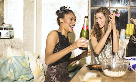 Two young women at a party in sequined dresses drinking and laughing, one holding a champagne bottle. Photographie de stock - Premium Libres de Droits, Code: 6118-09039255