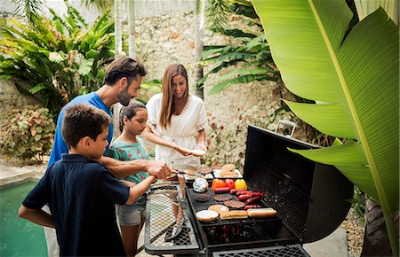 simsearch:6118-08991513,k - A family standing at a barbecue cooking food. Foto de stock - Royalty Free Premium, Número: 6118-09039206