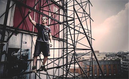 simsearch:6118-09039293,k - Young man standing on scaffolding on the outside of a city building. Photographie de stock - Premium Libres de Droits, Code: 6118-09039223