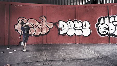 simsearch:6118-09039292,k - Young man playing with a ball in front of a wall of graffiti. Foto de stock - Sin royalties Premium, Código: 6118-09039222