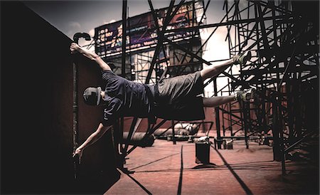simsearch:6118-08991633,k - A parcour runner swinging from a scaffolding pole. Stock Photo - Premium Royalty-Free, Code: 6118-09039224