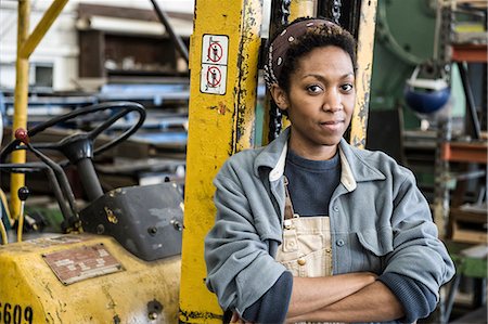 Black woman factory worker and a fork lift in a sheet metal factory. Stock Photo - Premium Royalty-Free, Code: 6118-09140097