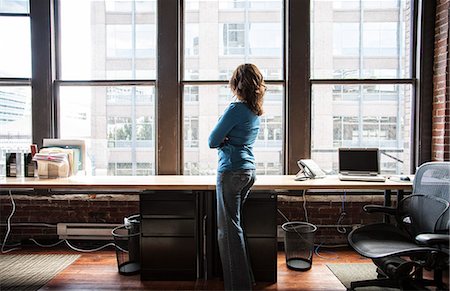 simsearch:6118-09139986,k - Caucasian woman at office workstation near a large bank of windows. Foto de stock - Sin royalties Premium, Código: 6118-09140003