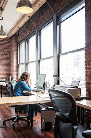 simsearch:6118-09139986,k - Caucasian woman at office workstation near a large bank of windows. Foto de stock - Sin royalties Premium, Código: 6118-09140001