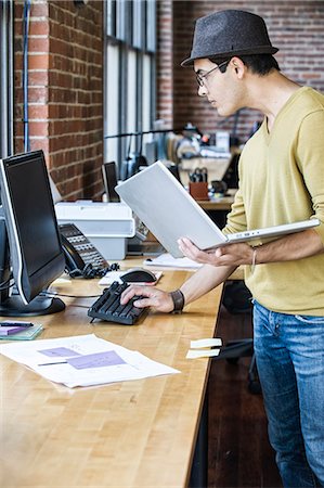 simsearch:6118-09139994,k - Hispanic male at his office workstation in a creative office. Foto de stock - Sin royalties Premium, Código: 6118-09140026