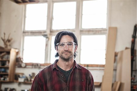 stubble - View of a Caucasian man factory worker wearing safety glasses in a woodworking factory. Stock Photo - Premium Royalty-Free, Code: 6118-09140147