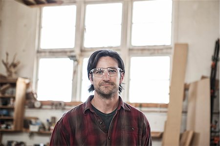 View of a Caucasian man factory worker wearing safety glasses in a woodworking factory. Foto de stock - Sin royalties Premium, Código: 6118-09140147