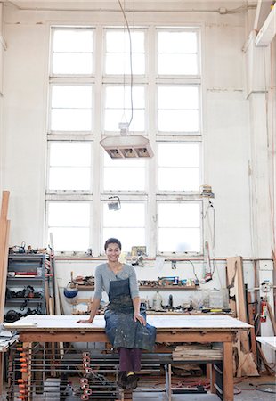 View of a smiling black woman factory worker at her work station in a woodworking factory. Foto de stock - Sin royalties Premium, Código: 6118-09140150