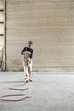 simsearch:6118-07351305,k - Black woman factory worker gathering tools together on the floor of a sheet metal factory. Stock Photo - Premium Royalty-Free, Code: 6118-09140109