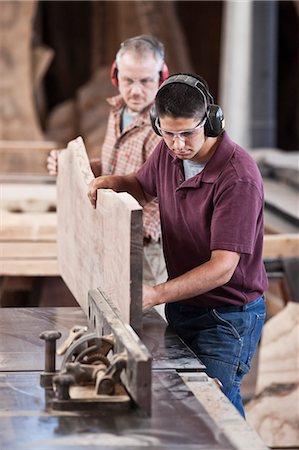 Team of two Caucasian men cutting a large  wooden slab on a table saw in a woodworking factory. Stock Photo - Premium Royalty-Free, Code: 6118-09140128