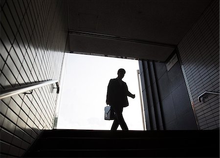 silhouette railway station - Low angle view of man carrying briefcase entering entrance to subway station. Stock Photo - Premium Royalty-Free, Code: 6118-09144794