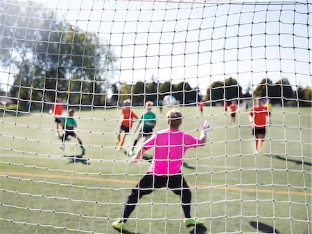 simsearch:614-06719868,k - Group of men playing football on grass soccer field, seen from behind net of goal. Stock Photo - Premium Royalty-Free, Code: 6118-09144856