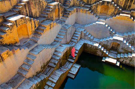 High angle view of woman wearing pink saris walking up stairwell around water pool of an ancient building. Stock Photo - Premium Royalty-Free, Code: 6118-09144864