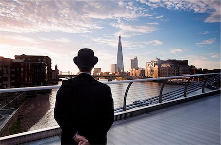 simsearch:6118-08842119,k - Rear view of man wearing black coat and Bowler hat standing on Millennium Bridge over the River Thames in London, England, the Shard skyscraper in the distance. Stock Photo - Premium Royalty-Free, Code: 6118-09144957