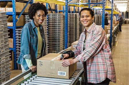 Team portrait of multi-ethnic female warehouse workers working next to a motorized feed conveyor in a large distribution warehouse. Stock Photo - Premium Royalty-Free, Code: 6118-09147869